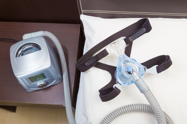 cpap_machine_with_mask_and_tubing_on_bedside_table