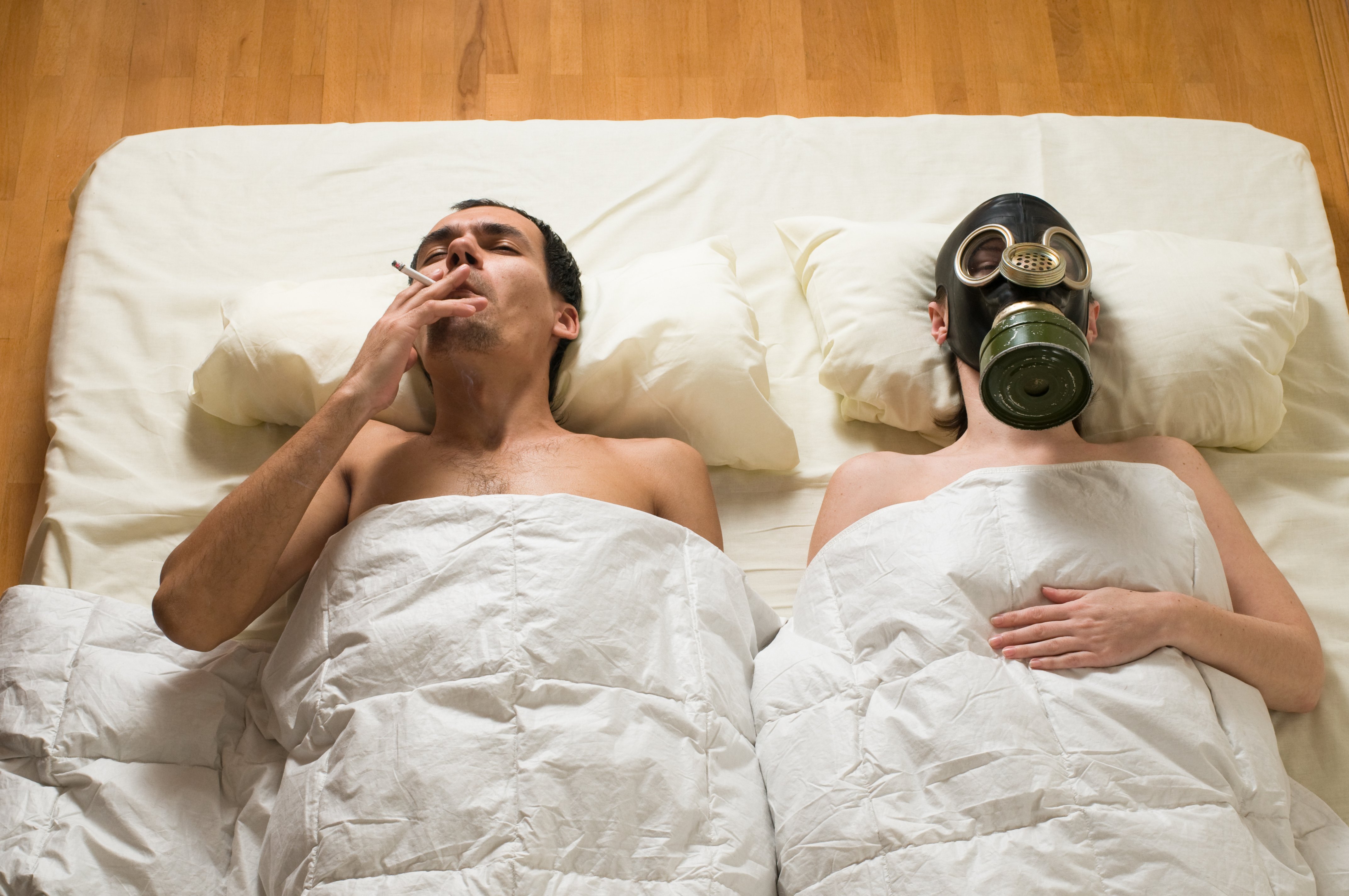 В постели с опасностью. Мужчины курят в постели. Сон в противогазе. Смешная фотосессия в кровати. Мужчина и женщина в противогазах.
